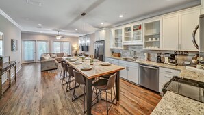 A modern kitchen with a dining area, wooden flooring, and built-in cabinets. - 5min Walk to Beach, Free Golf Cart, Pool, Luxe Townhome (Miramar Beach)