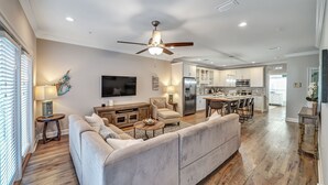 A spacious living room with a large gray sofa, a ceiling fan, and a flat-screen TV. - 5min Walk to Beach, Free Golf Cart, Pool, Luxe Townhome (Miramar Beach)