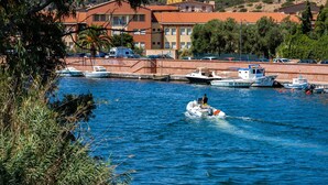 A marina with boats docked, a person on a jet ski, and buildings in the background. - Stunning home in Bosa (Bosa)