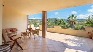 A balcony with wicker furniture, a view of a hilly landscape, and a clear sky. - Stunning home in Bosa (Bosa)
