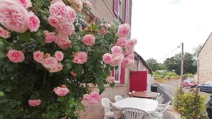 A patio with a round table and chairs, surrounded by pink roses.