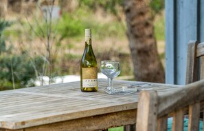 En flaska Adobe Reserve-vin och ett glas på ett träbord utomhus.