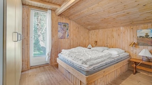 Ein Zimmer mit Holzboden, einem Bett, einem Fenster und einem Bild an der Wand.