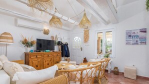 Un salon confortable avec un téléviseur, des meubles en bois et une vue sur l’extérieur.