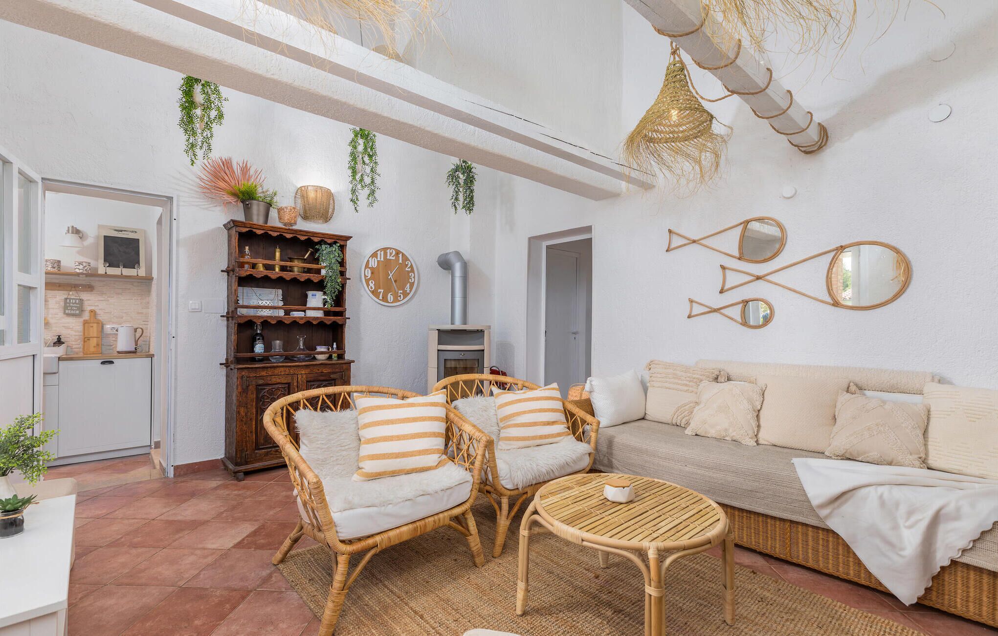 A cozy living room with wicker furniture, a round table, and a sofa with striped cushions.