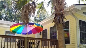 A covered patio with a colorful umbrella, a wooden deck, and a white fence.