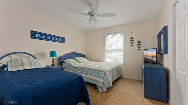 A bedroom with two beds, a ceiling fan, a television, and a sign that reads 'BEACH HOUSE'. - JANUARY-MAY 3 NIGHT MIN 2026 5 Bedroom3 bath 1 block to the beach and boards (Wildwood)