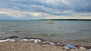A rocky shoreline with a yellow lifebuoy and a buoy in the water.