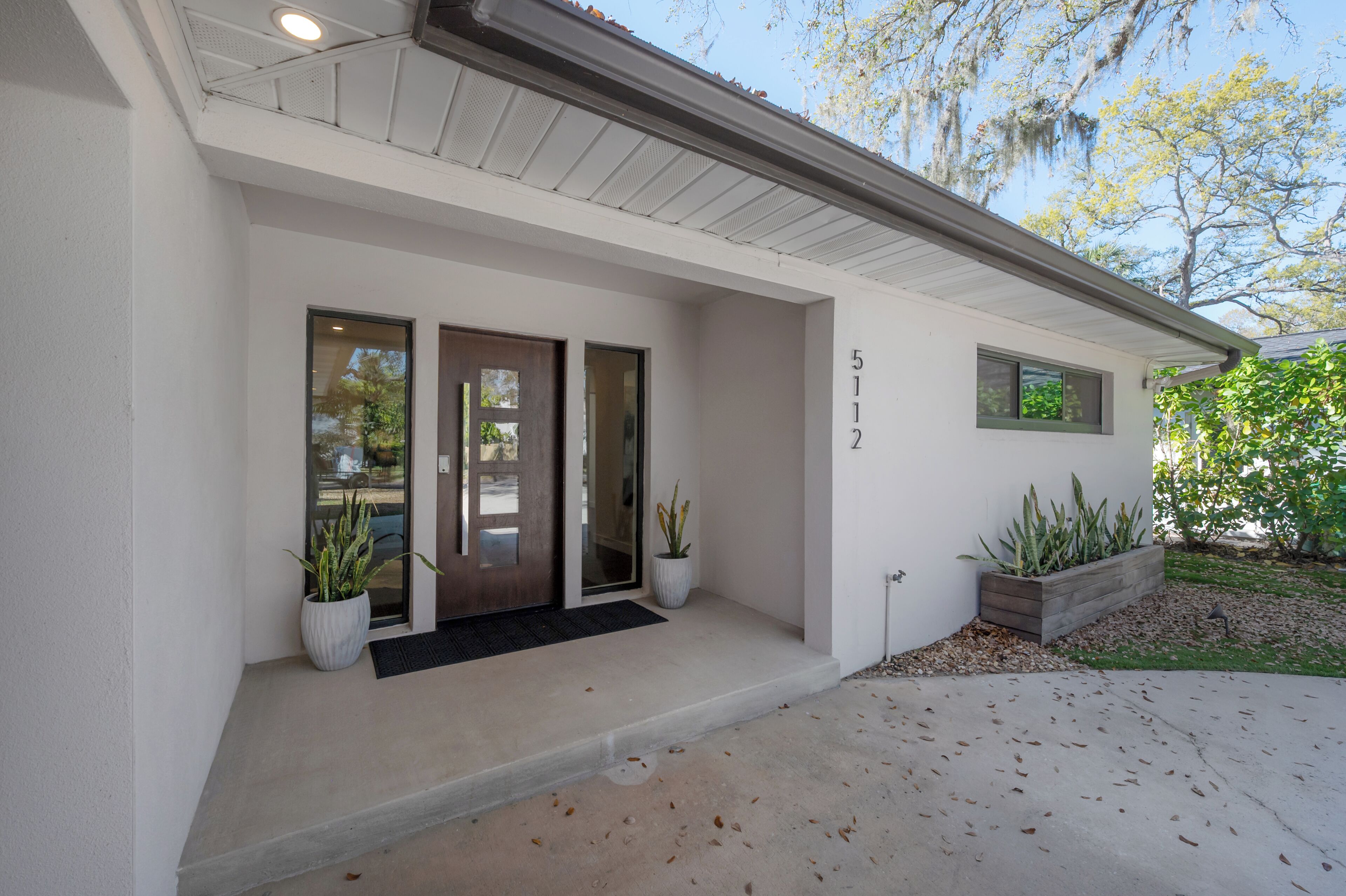 A modern house with a white exterior, a front door, and a mailbox.