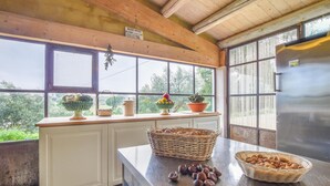 Eine Küche mit weißen Schränken, einem Edelstahl-Kühlschrank und einem großen Fenster mit Blick ins Grüne.