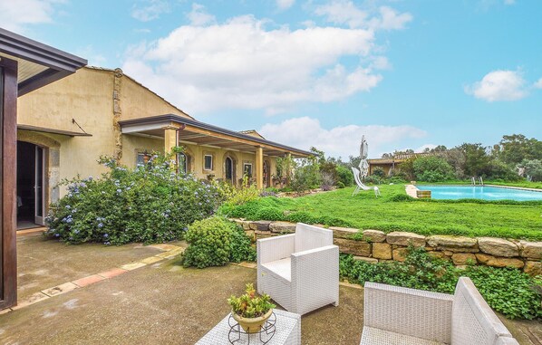 Relax in a serene outdoor setting with a well-maintained lawn and pool, surrounded by lush greenery.