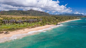 An aerial view of a coastal resort with beachfront properties, lush greenery, and mountains in the background. - BEST Ocean View in the Resort...Stunning & Panoramic!  Completely Renovated 2BR (Lihue)