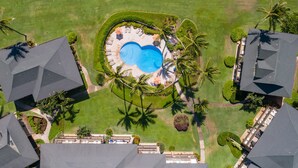 An aerial view of a resort with a central swimming pool surrounded by palm trees and manicured lawns. - BEST Ocean View in the Resort...Stunning & Panoramic!  Completely Renovated 2BR (Lihue)