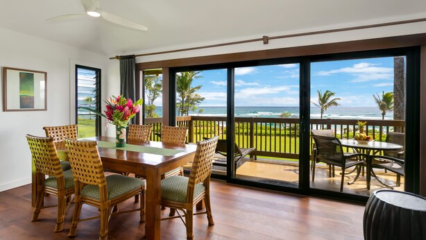 A dining area with a table and chairs, a ceiling fan, and a view of the ocean through large windows. - BEST Ocean View in the Resort...Stunning & Panoramic!  Completely Renovated 2BR (Lihue)
