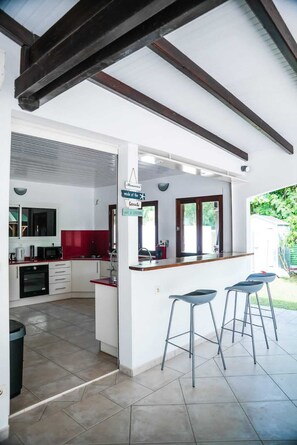 Une cuisine moderne avec des meubles blancs, un pare-feu rouge et un coin bar équipé de tabourets.