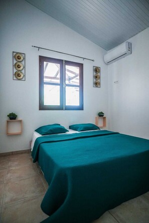Une pièce avec un lit, une fenêtre et un climatiseur fixé au mur.