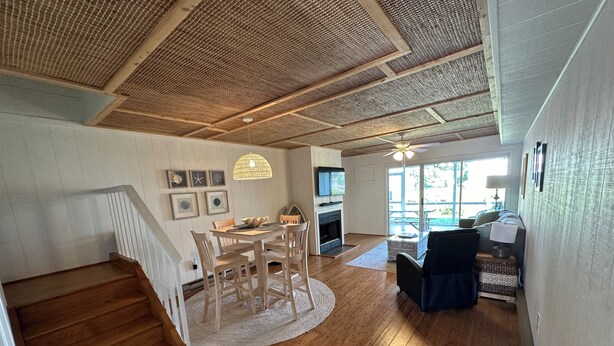 Un vaste espace de vie doté d’un plancher en bois, d’une table à manger avec des chaises, d’une cheminée et d’un escalier menant à un autre niveau.