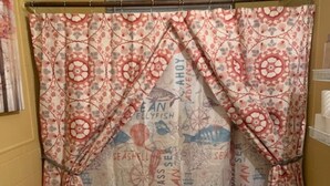 Une salle de bain avec un rideau de douche orné de motifs et d’inscriptions sur le thème de la marine, des toilettes et un petit lavabo.
