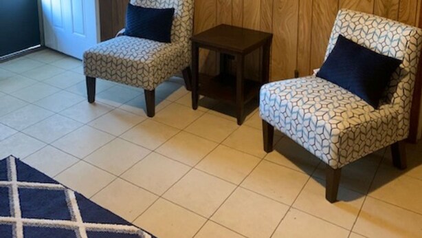 Une pièce comprenant deux fauteuils à motifs, une petite table et un miroir au mur.