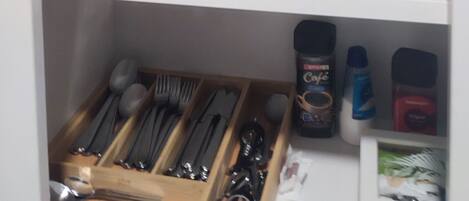 A kitchen cabinet with stacked plates, bowls, and utensils.