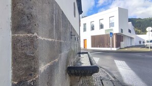 A modern building with a white facade, a wooden fence, and a paved street.
