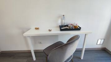A white desk with a tray of items including a water bottle, glasses, and cups.