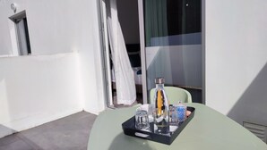 A balcony with a table set for tea, featuring a tray with a bottle, glasses, and a cup.