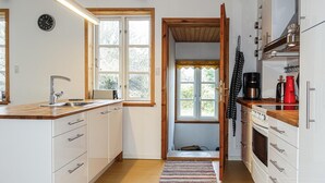 Een compacte keuken met witte kastjes, een houten aanrecht, een spoelbak en een koffiezetapparaat.
