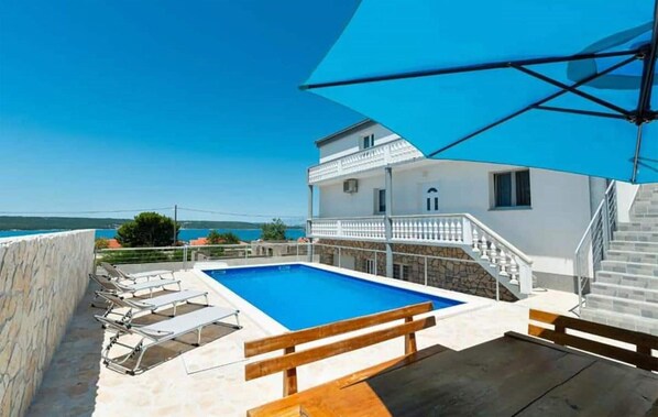 Relax by the pool with a serene sea view from the spacious outdoor area.