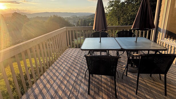 Une terrasse en bois avec une table et des chaises, offrant une vue sur un paysage magnifique.