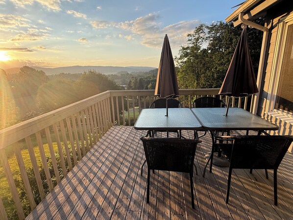 A wooden deck with a table and chairs, overlooking a scenic landscape. - Cozy Home with Stunning Views in Linville Falls (Newland)