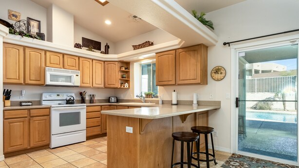 Una cocina con armarios de madera, una isla central y vista a una piscina.