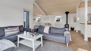 Una sala moderna con un sofá gris, una mesa de centro blanca y una chimenea negra.