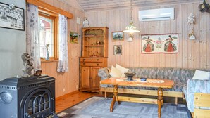 Una habitación acogedora con paredes de madera, un sofá, una mesa de madera, una estufa y varios adornos.