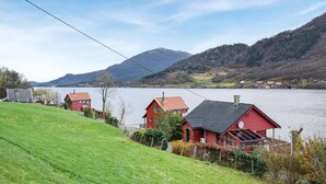Una hilera de casas rojas con un lago y montañas al fondo.