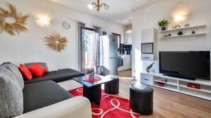 A modern living room with a sofa, red rug, and a TV.