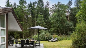 Eine Terrasse mit Gartenmöbeln, einem Grill und einem großen Sonnenschirm.