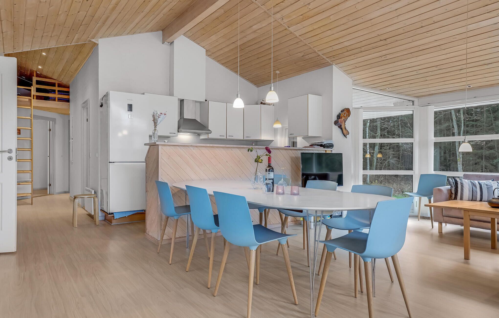 A modern kitchen with white cabinets, a central island, and blue chairs.