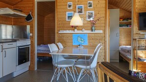 Cocina compacta con estufa, horno y pileta, comedor con mesa y sillas, y dormitorio con cama y televisor.