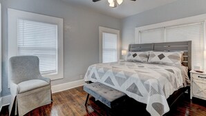 Une chambre à coucher comprenant un lit, une chaise, une table de chevet et un ventilateur de plafond.