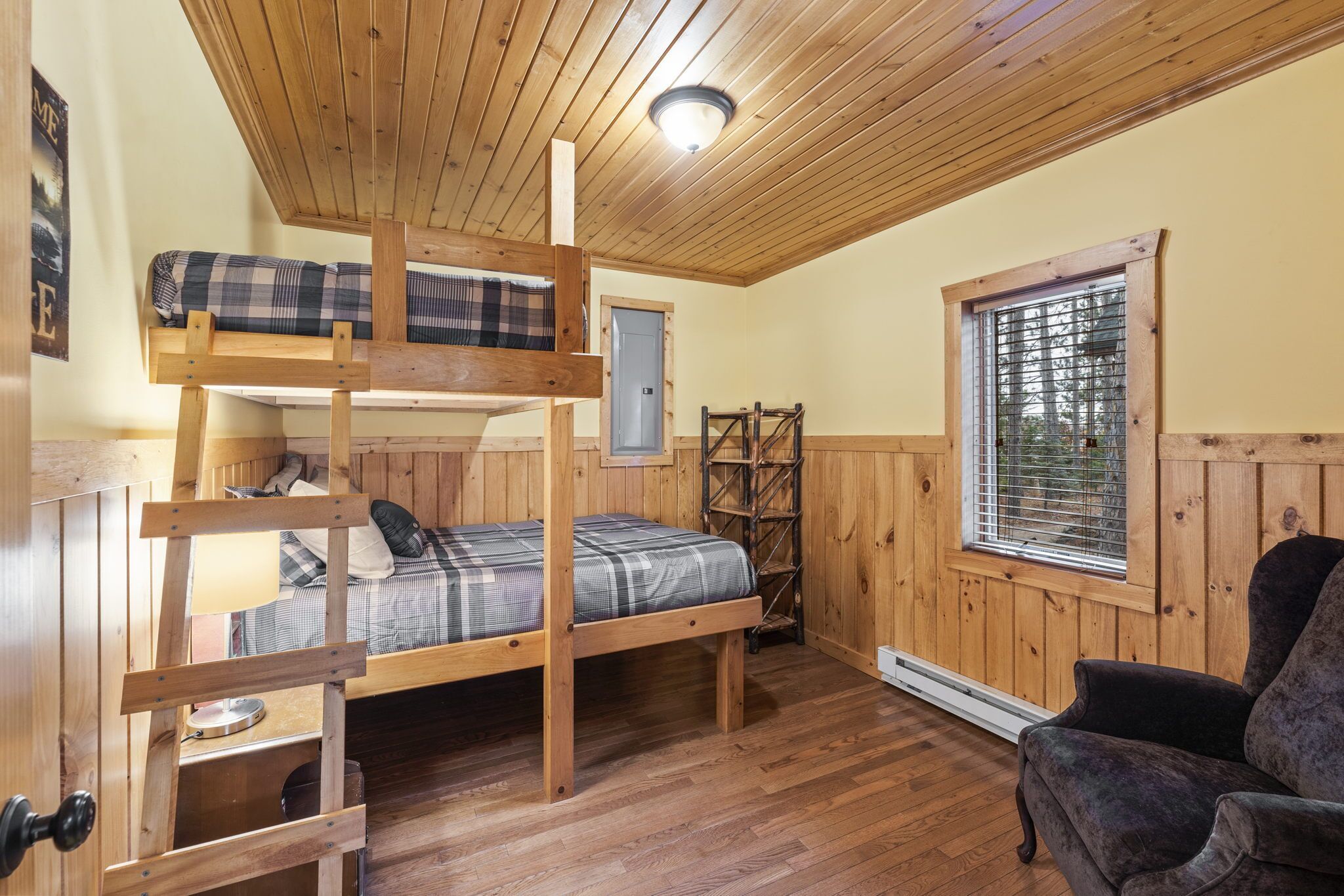 Dormitorio con literas, paredes de madera y ventana con persianas.