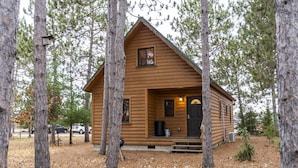 Une cabane en rondins avec un porche à l’avant, une petite fenêtre et une porte.
