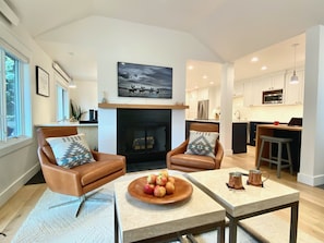 A modern living room with leather armchairs, a fireplace, and a dining area with a table and apples.
