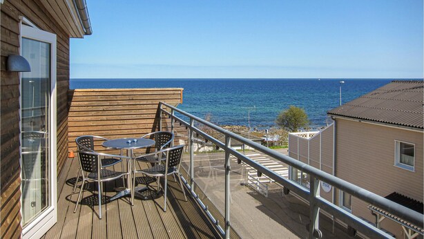 Een balkon met een tafel en stoelen, met uitzicht op zee.