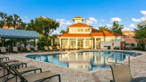 A pool area with lounge chairs and a building with a red roof. - Exceptional Condo on the Bradenton Riverwalk (Bradenton)