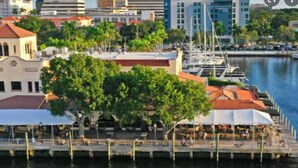 A waterfront area with a dock, a covered seating area, and buildings in the background. - Exceptional Condo on the Bradenton Riverwalk (Bradenton)