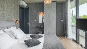 A modern bedroom with a large bed, a bedside table, a mirror, and a view of greenery outside. - Lovely home in Zminj with sauna (Zminj)