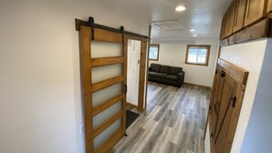 Une pièce spacieuse dotée d’une porte coulissante en bois, d’un canapé et d’un réfrigérateur.
