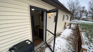 Une maison de plain-pied avec une porte-fenêtre coulissante, une poubelle et une clôture en bois.