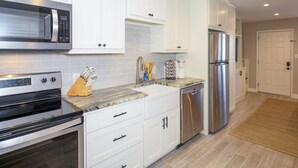 A modern kitchen with white cabinets, stainless steel appliances, and a granite countertop.